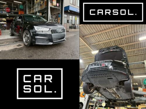 アウディ車両をリフトアップし、車検見積りのための下回り点検を開始している様子。工場内で整備士が作業に入る前の状態。