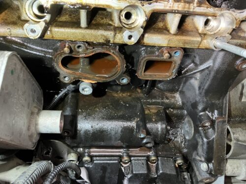 ゴルフ6 GTI ウォーターポンプ交換 修理時の冷却水漏れ確認状況 ゴルフ6 GTIのウォーターポンプ取り外し後のエンジン側接合部の状態。 冷却水が溜まっている様子や、ガスケット接触面にサビや劣化跡が見られる状況を撮影した写真。 ウォーターポンプ周辺からの冷却水漏れが確認できる作業途中の状態。