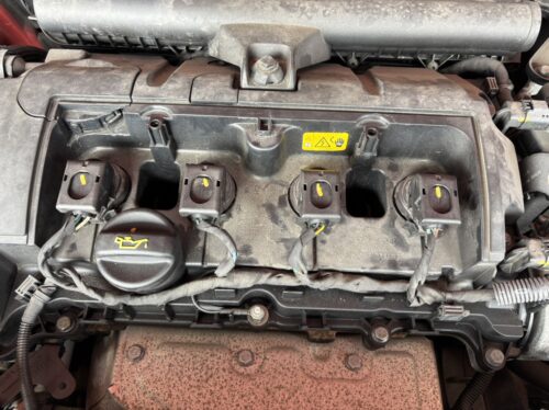 MINIクロスオーバーのエンジン不調修理に伴い、エンジンカバーを取り外し、イグニッションコイルおよびスパークプラグ周辺を点検している作業前のエンジンルーム写真。