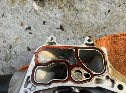 VWパサートヴァリアントのオイルクーラー接合部の拡大写真。赤色のガスケットが装着された状態で、オイルの付着や劣化の様子が確認できる構図。