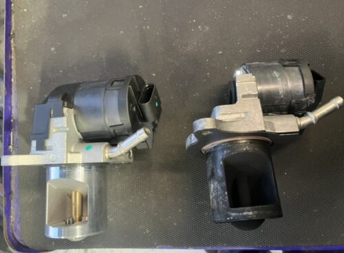 ベンツGLクラス エンジンチェックランプ修理 EGRバルブ交換 新旧部品比較 ベンツGLクラスのEGRバルブ交換作業で、新品のEGRバルブ(左)と取り外した旧EGRバルブ(右)を並べて比較している写真。旧部品には排気ガスによるカーボン汚れが付着している状態。