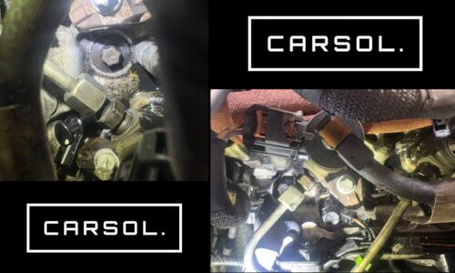 プジョー308のエンジン内部を点検している様子。シリンダーヘッド周辺やスロットル付近にオイルの付着が見られ、ガスケット劣化によるオイル漏れを確認している整備点検の状態。