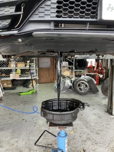 リフトアップした車両の下からエンジンオイルを排出している様子