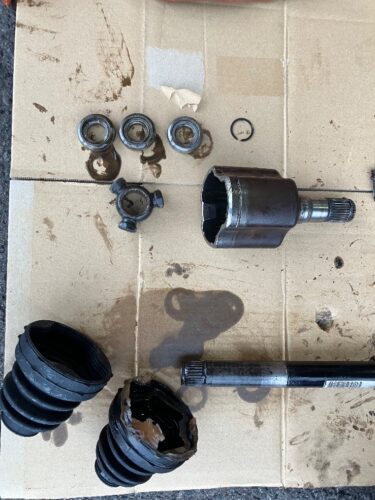 取り外したドライブシャフトと分解した内部部品、破れたドライブシャフトブーツからグリスが漏れている状態