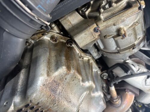 エンジン下部のクーラーハウジング周辺にオイルが滲み、汚れている状態（オイル漏れ箇所の実写）