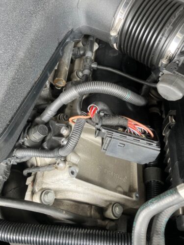BMW M6 エンジンチェックランプ修理でイオン電流センサー関連部品を交換している作業中の様子 BMW M6のエンジンルーム内でイオン電流センサー関連部品を交換している作業中の様子。配線コネクターを取り外し、故障診断に基づいて部品交換を進めている場面。