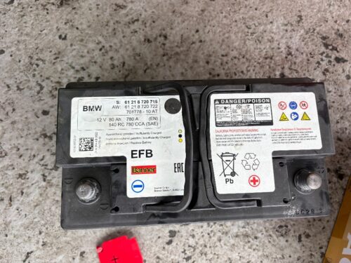 取り外したBMW純正EFBバッテリーの単体写真。交換前のバッテリー状態を記録したもので、経年劣化による性能低下が確認された部品の様子。
